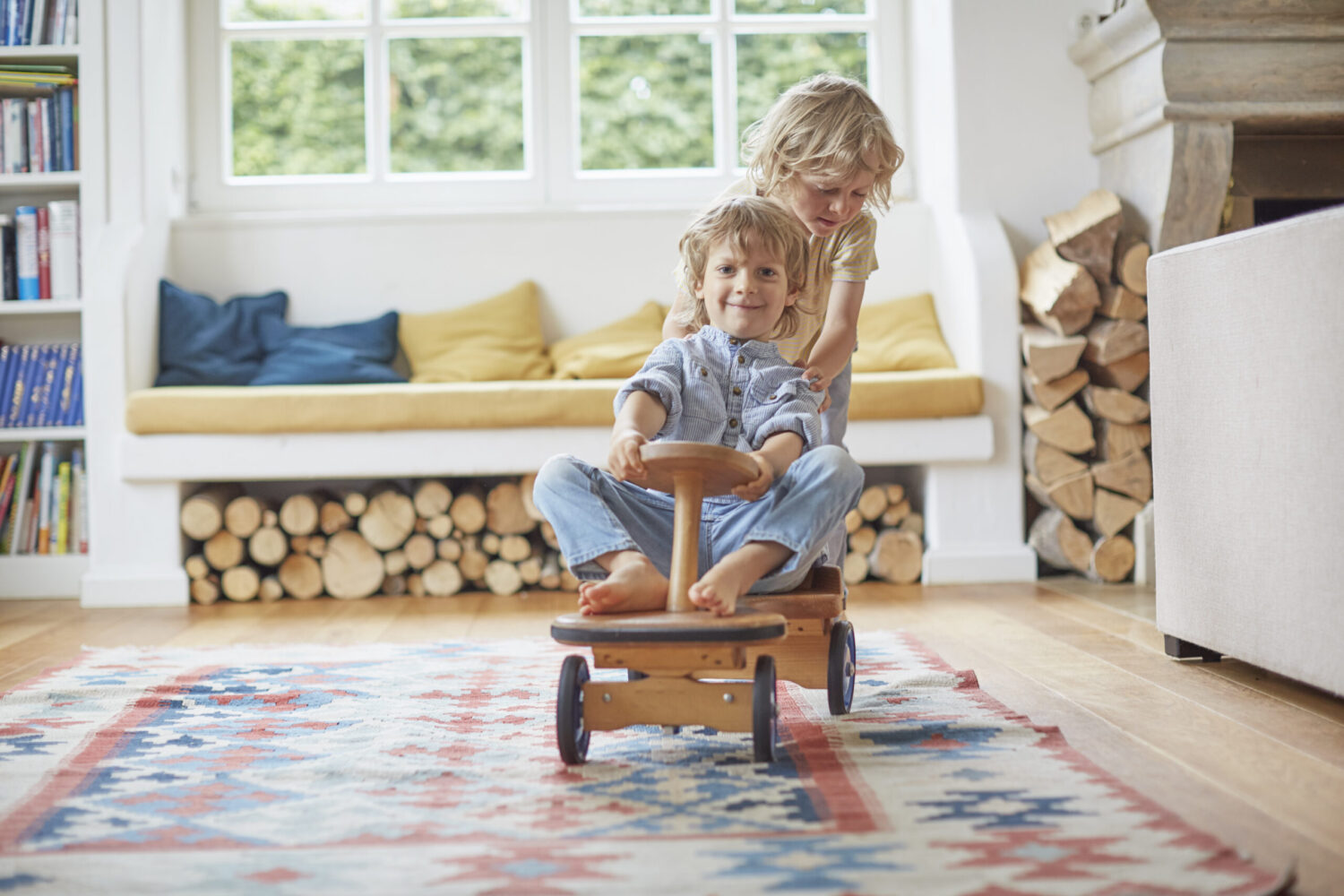 Two young brothers playing with wooden toy car